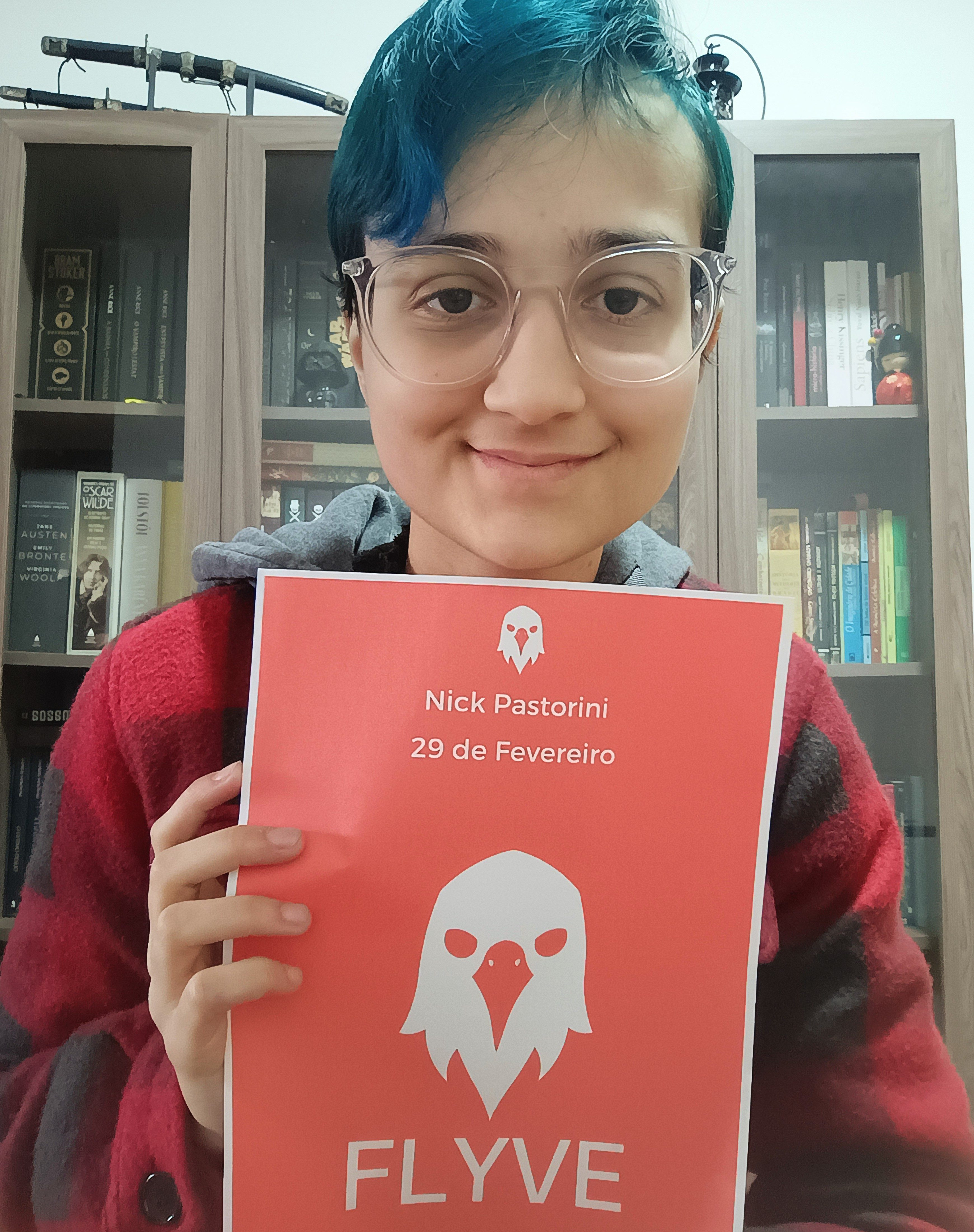 Um jovem de ocúlos e cabelo azul curto segurando o contrato da editora. 
